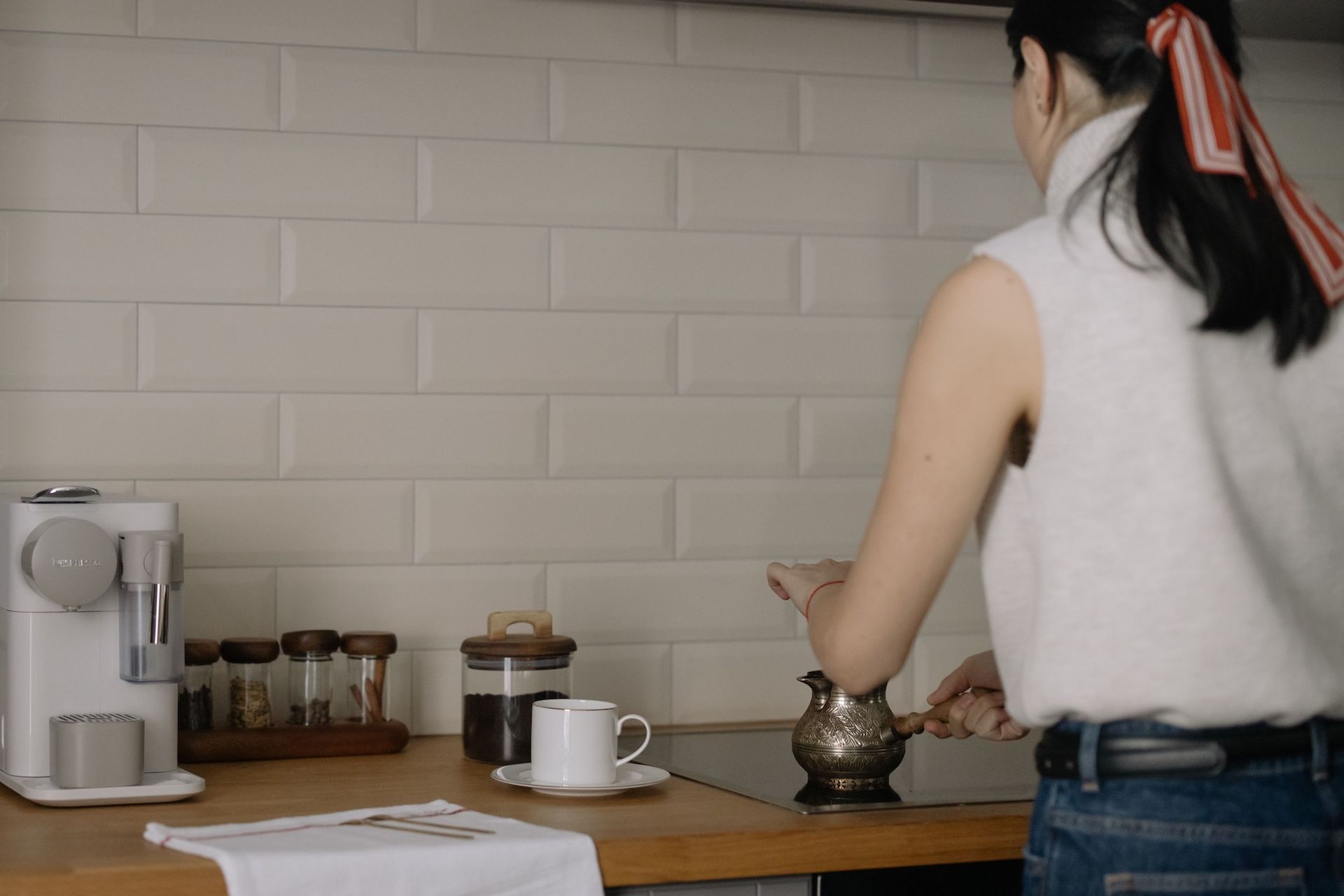 A woman stands by a kitchen counter, showcasing her home coffee bar while preparing coffee.