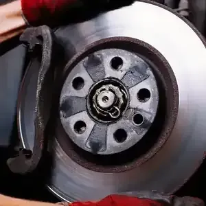 Close-up of a car brake disc and caliper with metallic rotor and wheel hub.