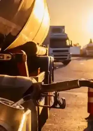 Soldiers in yellow helmets with rifles beside a military truck on a road at sunset