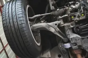 Close-up of a car’s front suspension and tire during maintenance, showing the wheel well and steering components.