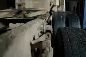 Close-up of a truck’s worn tire and dusty undercarriage in a garage