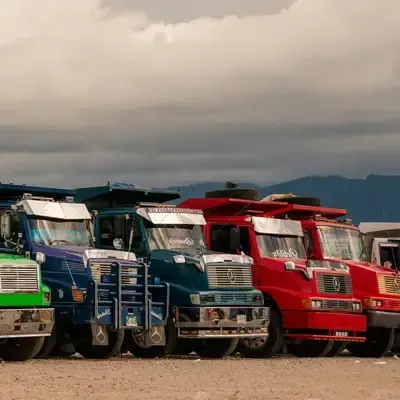 Row of colorful semi trucks parked side by side under a cloudy sky