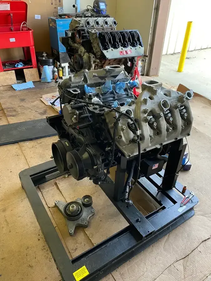 Engine block on a stand in a workshop, with tools and a red cabinet in the background.