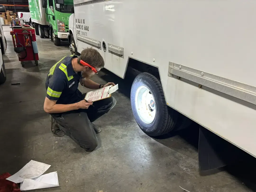 Person working inside a yellow vehicle in a dim garage, examining the open side panel.