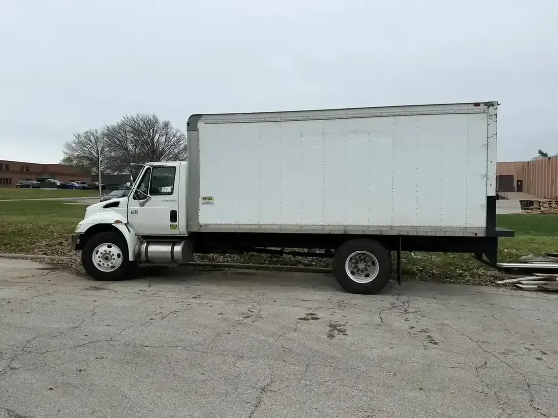 White box truck parked on a paved lot under an overcast sky