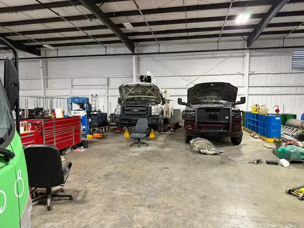 Auto repair shop with two raised vehicles, tools, and equipment inside a garage