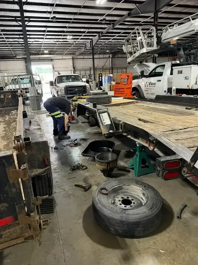 Worker power-washing the floor between parked trucks in a loading bay
