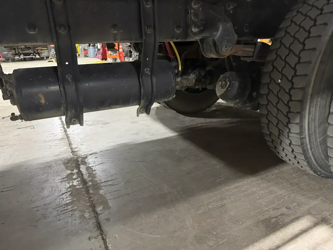 Row of black metal tanks or cylinders mounted on a vehicle chassis with orange fittings