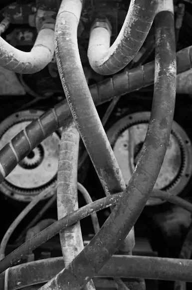 Black-and-white close-up of tangled hoses and cables in front of round gauges or dials