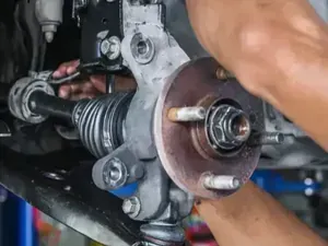 Mechanic holding a car wheel hub and axle assembly during repair