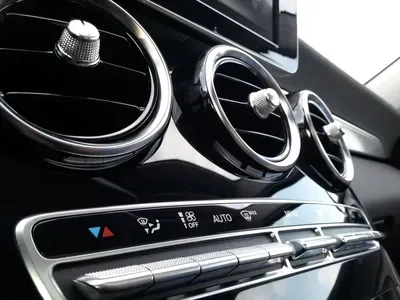 Close-up of a car dashboard with chrome air vents and climate controls
