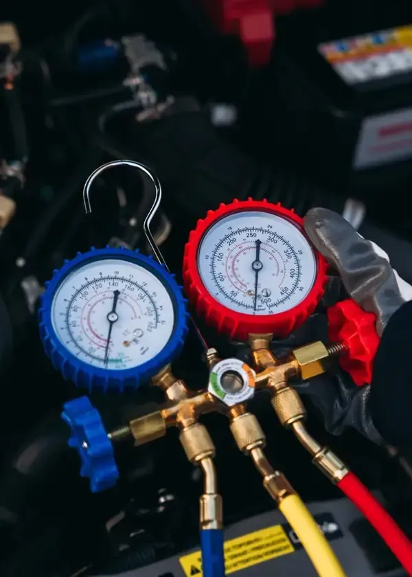 Blue and red pressure gauges on HVAC manifold with attached hoses and valves