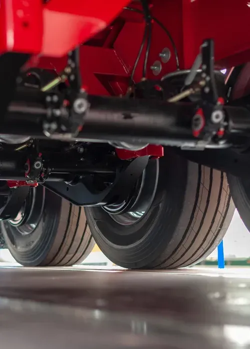 Close-up of truck dual rear tires and suspension on a red vehicle in a garage