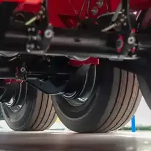 Close-up of a vehicle’s dual rear wheels and suspension beneath a red chassis.