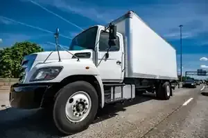 White box truck parked on a roadside under a clear blue sky