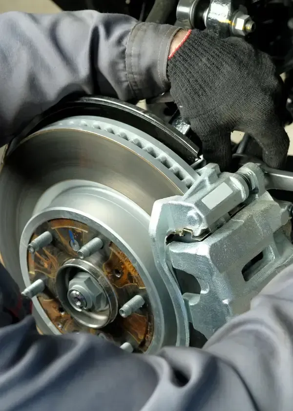 Mechanic’s gloved hands working on a car brake rotor and caliper assembly