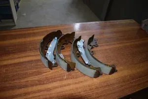 Four curved metal brake shoes or pads arranged on a wooden table.