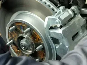 Close-up of a car brake rotor and caliper assembly with exposed lug studs.