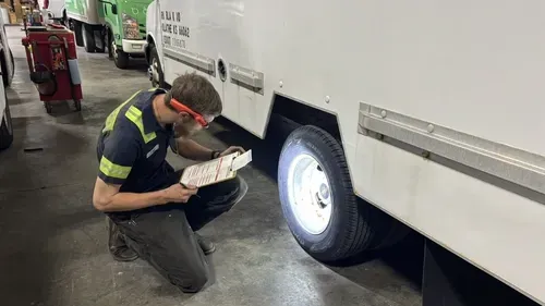 Technician in hard hat operating a control panel on a lime-green industrial truck