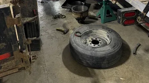 Close-up of a truck’s worn tire and dusty undercarriage in a garage