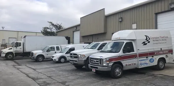 White service vans parked outside an industrial warehouse on an overcast day