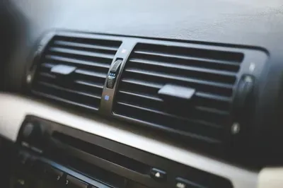 Close-up of a car dashboard air vent and center console in dark gray