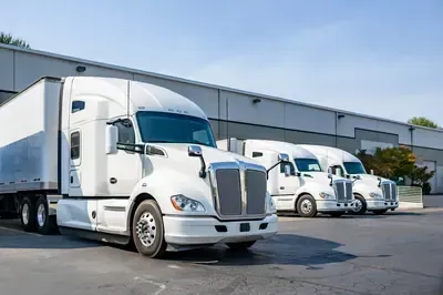 White semi-trucks parked outside a warehouse on a sunny day