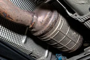 Rusty metal exhaust pipe with a flex joint beneath a vehicle chassis