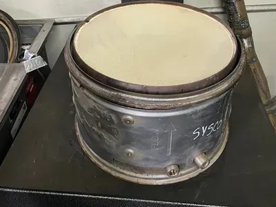 Metal cylindrical container with a cream-colored liner and handwritten label on a workbench