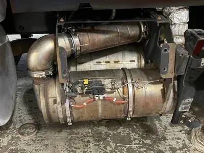 Close-up of a truck’s undercarriage with two metal cylindrical tanks and exhaust piping under the frame