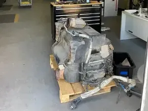Damaged car transmission and parts on a pallet in a workshop floor
