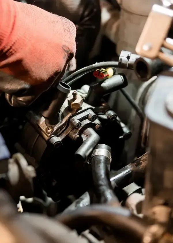 Mechanic's gloved hand working on car engine wiring and hoses close-up
