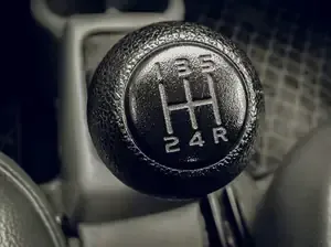 Close-up of a manual car gear shift knob showing a 5-speed shift pattern with reverse.