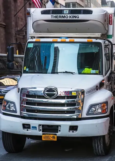 White Thermo King refrigerated truck parked in a narrow alley, front view.