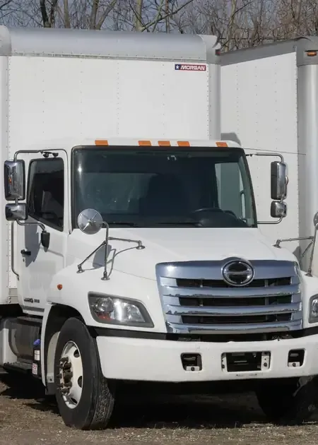 White commercial truck parked in front of a white trailer building outdoors