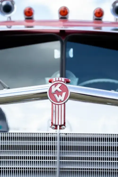 Close-up of a red-and-chrome Kenworth truck grille and hood ornament