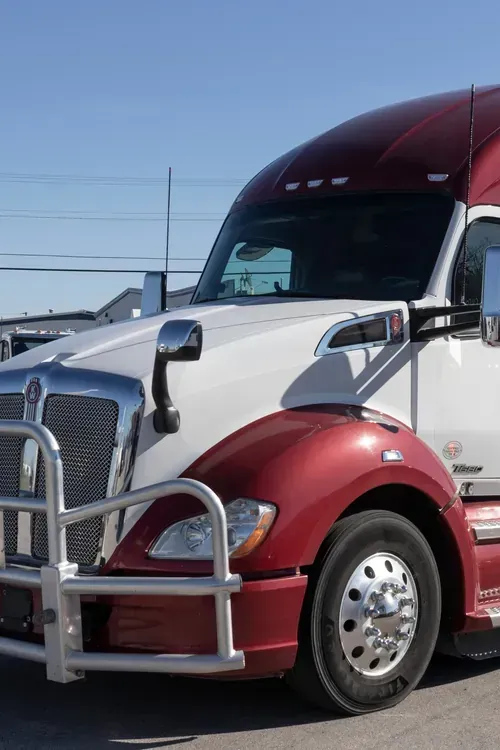 Red semi-truck parked outdoors under a clear blue sky