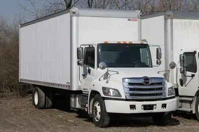 White box truck parked outdoors beside another truck.