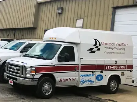 White delivery van with Champion FleetCare logo parked outside a warehouse building