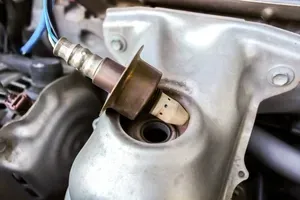 Oxygen sensor mounted in a metal exhaust manifold, close-up of engine hardware