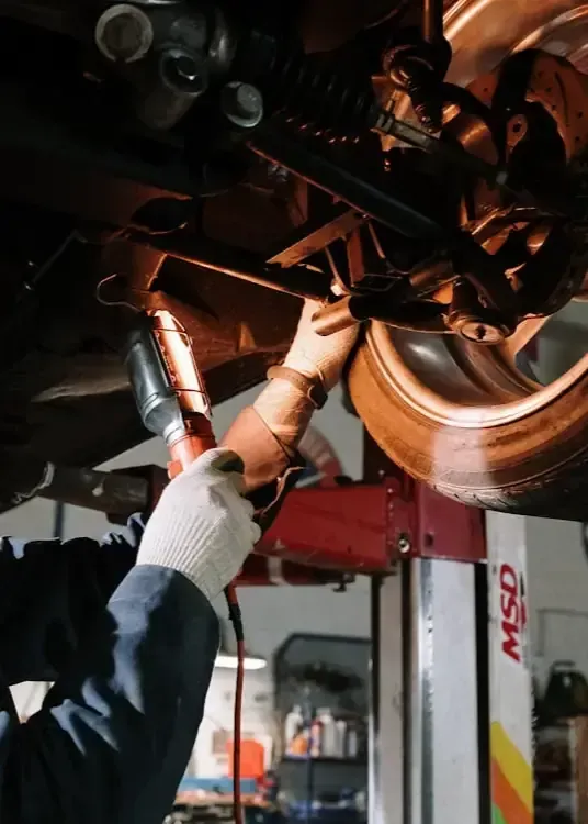 Mechanic using tools to work under a vehicle in an auto repair shop