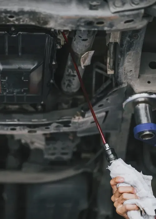 Person using a long tool to work under a vehicle in a garage