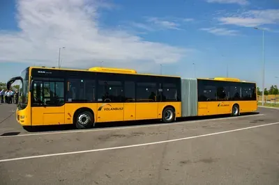 Yellow articulated city bus on an empty road under a blue sky
