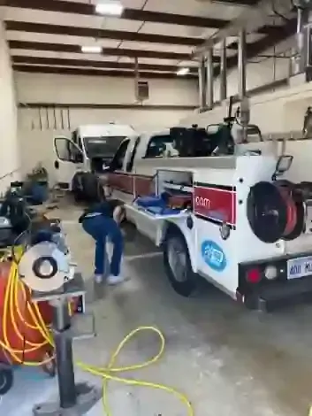 Tow truck in a garage while a person works beside it