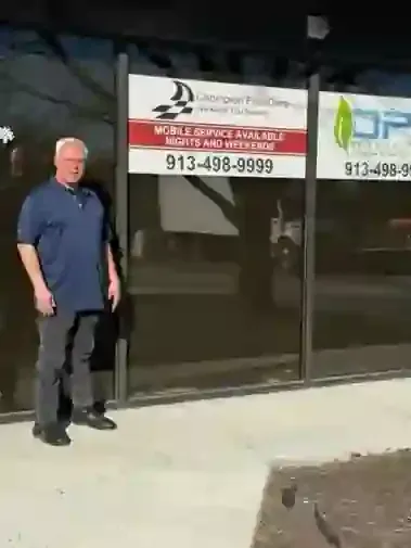 Man standing outside a storefront with a sign for mobile service and phone number 913-498-9999