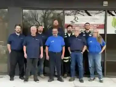 Group of uniformed workers standing outside a building entrance, posing for a team photo