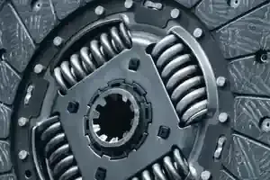 Close-up of a car clutch disc with metal springs and worn gray friction surface