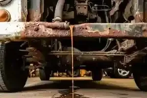 Underside of a rusty truck on a lift, with wheels and suspension visible in a garage.