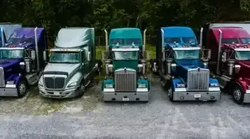 Five colorful toy semi-trucks lined up outdoors on pavement
