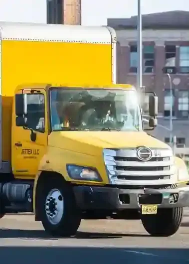 Yellow box truck parked on a street, front view with silver grille and cab.